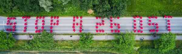 105 rote Regenschirme bilden 84 Meter lange Parole auf der Kornweide als Protest gegen die geplante A26-Ost